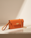 La Pochette en cuir de vachette 2ᵉ fleur, coloris Orange, fermoir tournant doré et chaîne