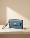 La Pochette en cuir de vachette 2ᵉ fleur, coloris Bleu, fermoir tournant doré et chaîne