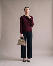 La Duchesse coloris gris éléphant portée à la main par l'égérie La Firkin, pull bordeaux et pantalon noir