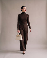 La Duchesse coloris blanc crème portée à la main par l'égérie La Firkin, pull col roulé et pantalon chocolat