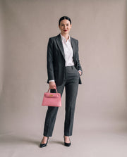 La Duchesse coloris rose portée à la main par l'égérie La Firkin, blazer gris anthracite et chemise blanche