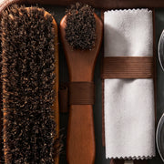 Détail de la trousse d'entretien du cuir La Firkin : brosse en crin, petite brosse à manche en bois et chiffon doux